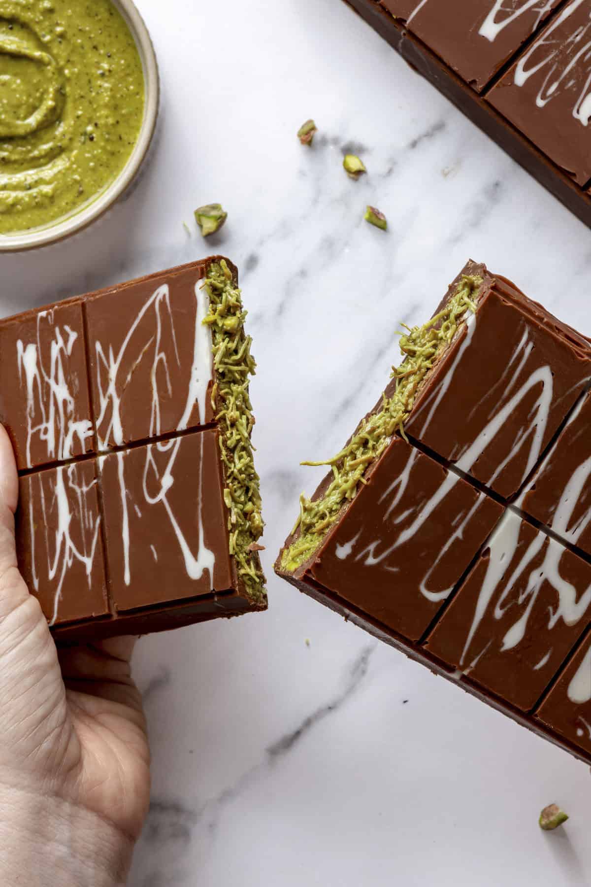 Hands splitting a homemade Dubai chocolate bar in half to show filling.