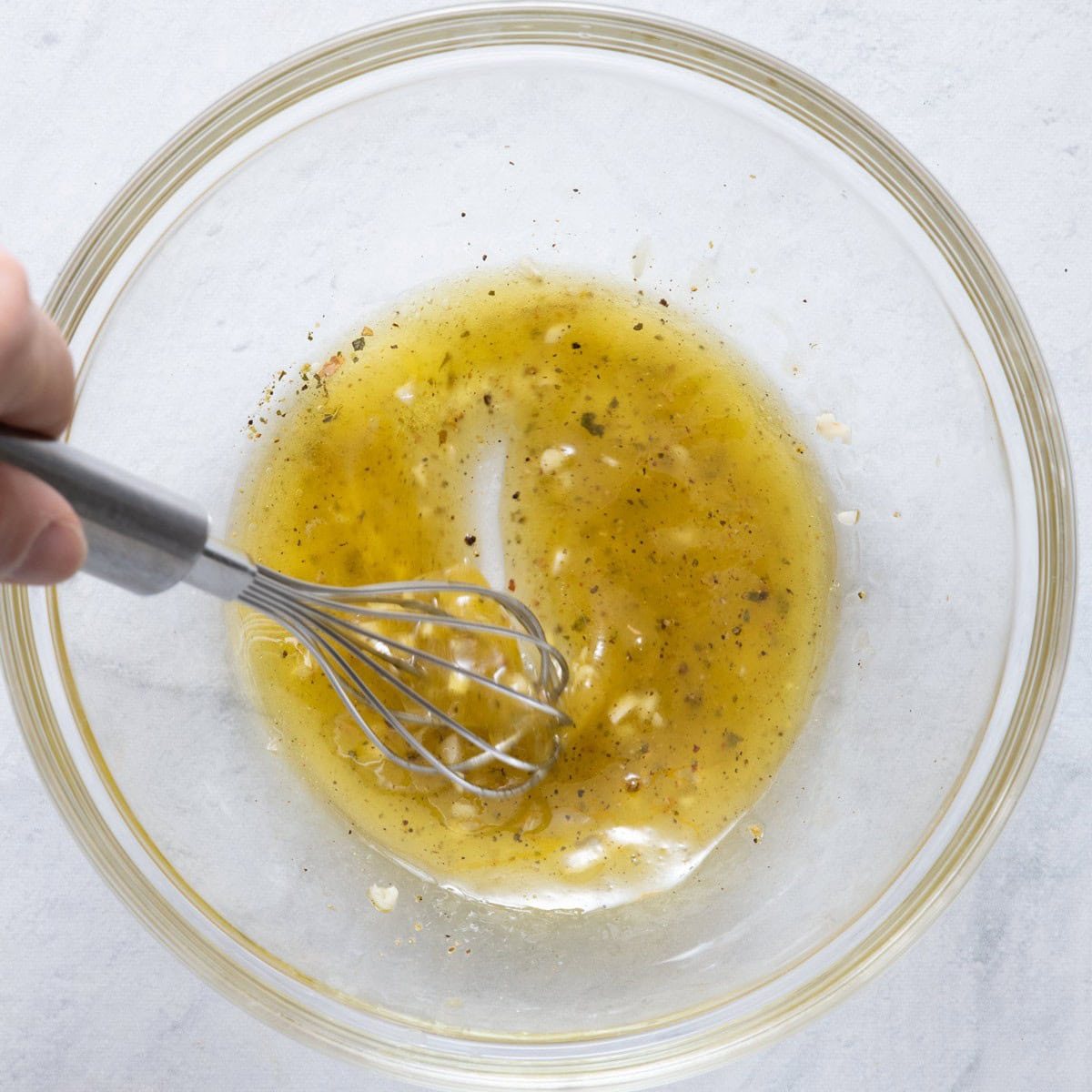 Dressing being whisked in a small bowl.