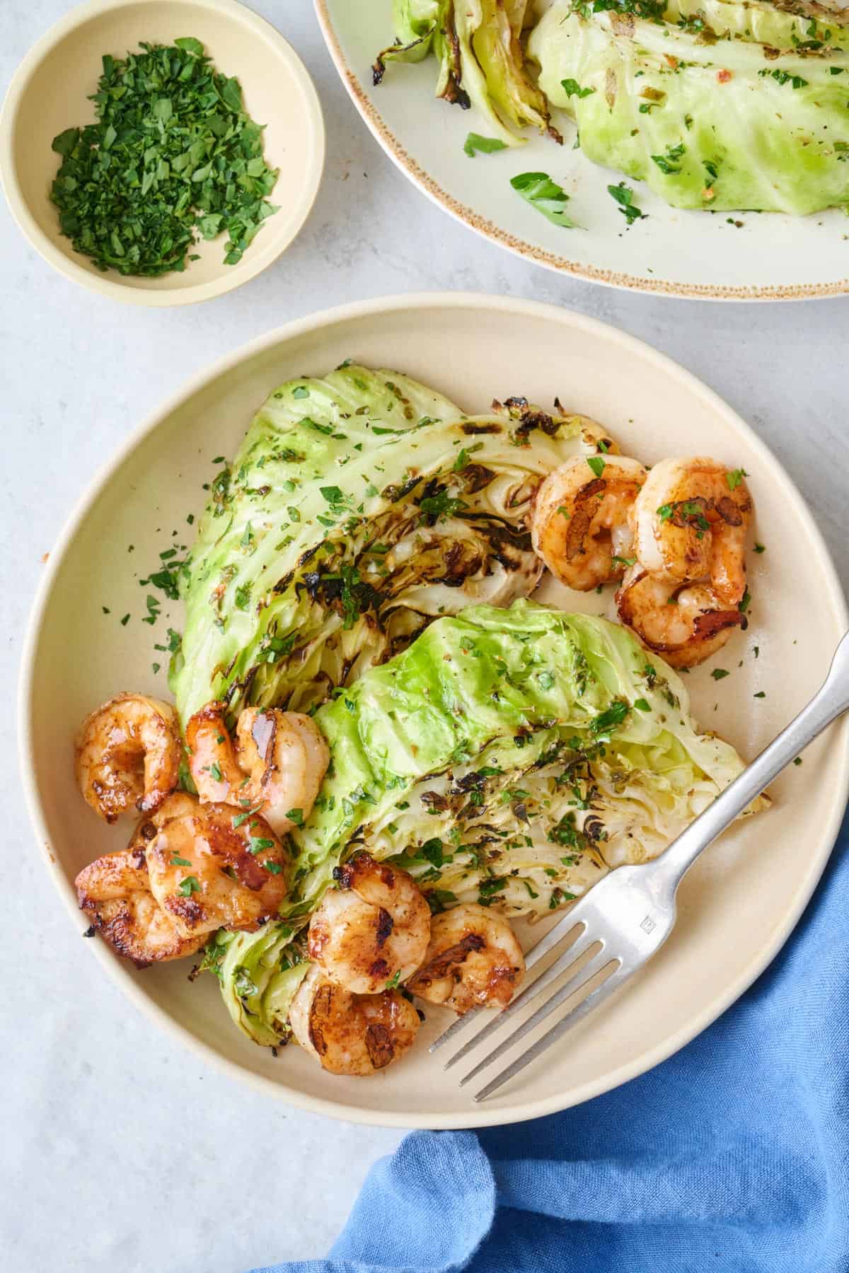 Grilled cabbage on a plate served with grilled shrimp.