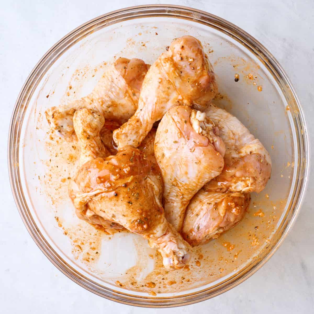 Chicken legs added to bowl and tossed in marinade.