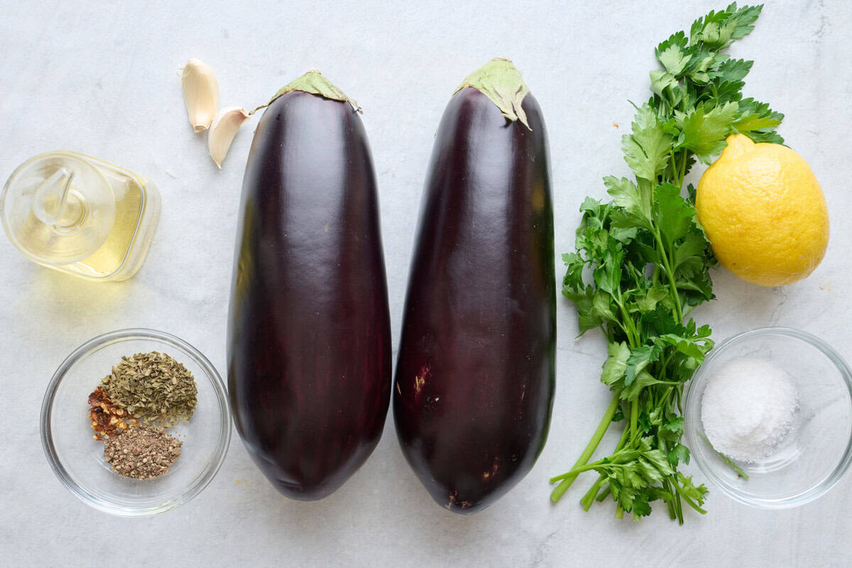 Ingredients for recipe: oil, garlic cloves, spices, eggplant, fresh parsley, lemon and salt.