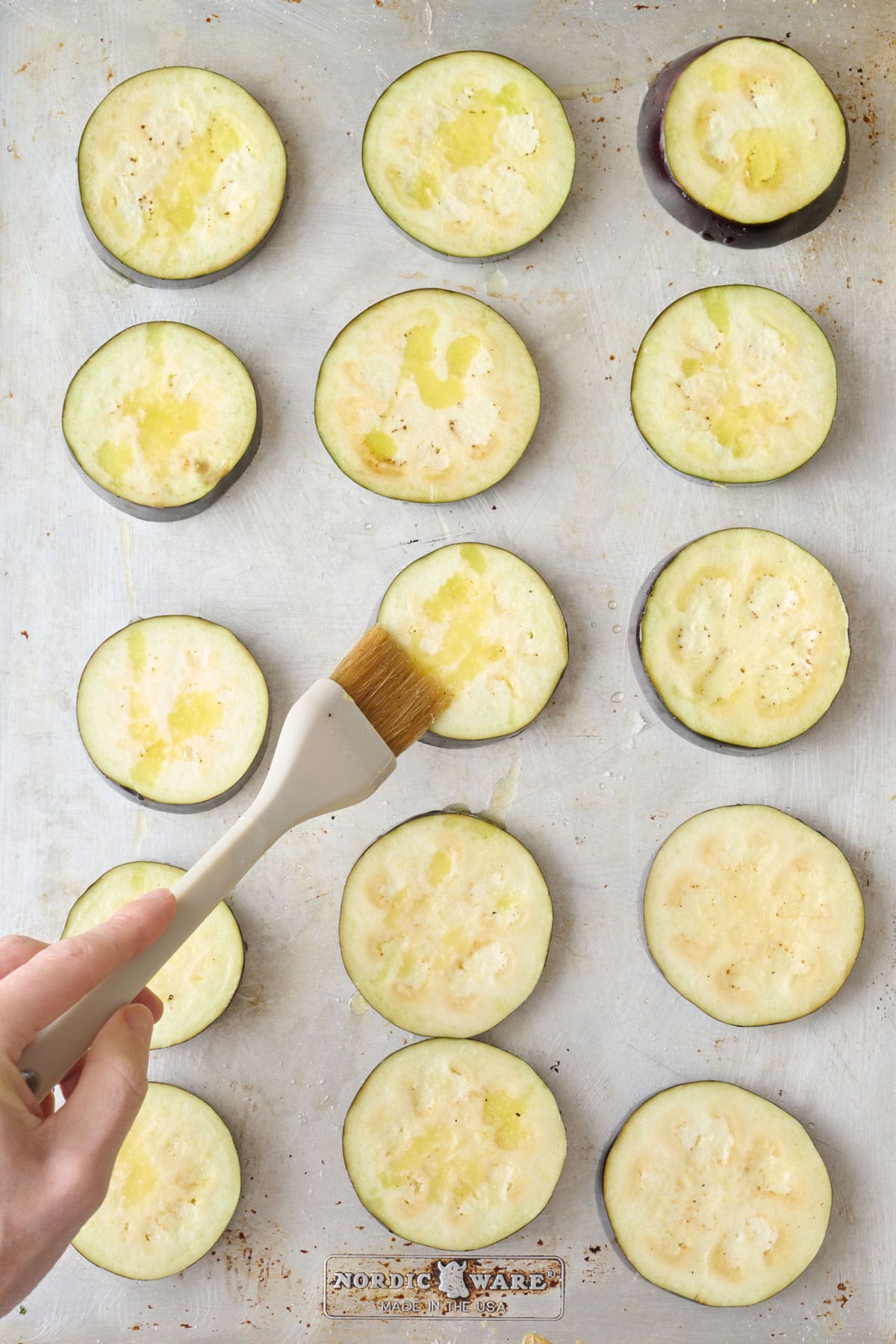 Brushing oil on eggplant rounds.