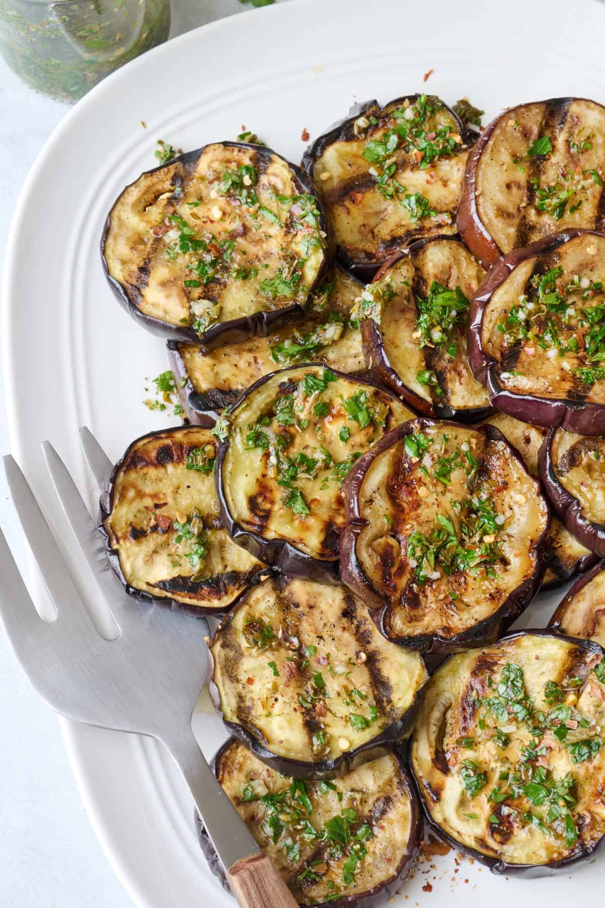 Grilled eggplant slices on a platter with sauce.
