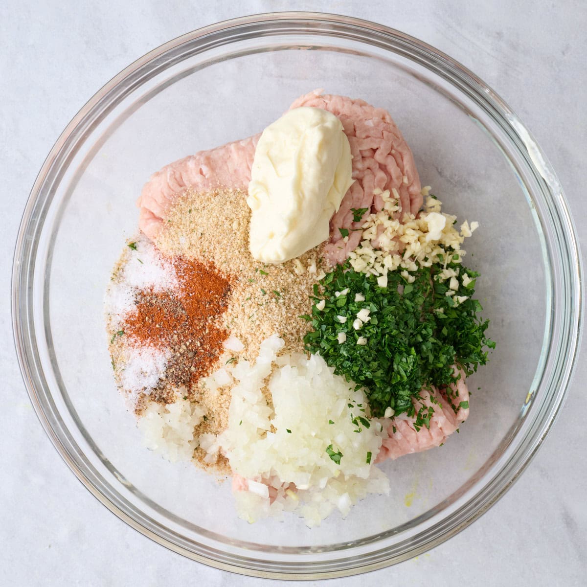 Ground chicken, breadcrumbs, mayo, onions, parsley, garlic, and seasonings in a bowl.