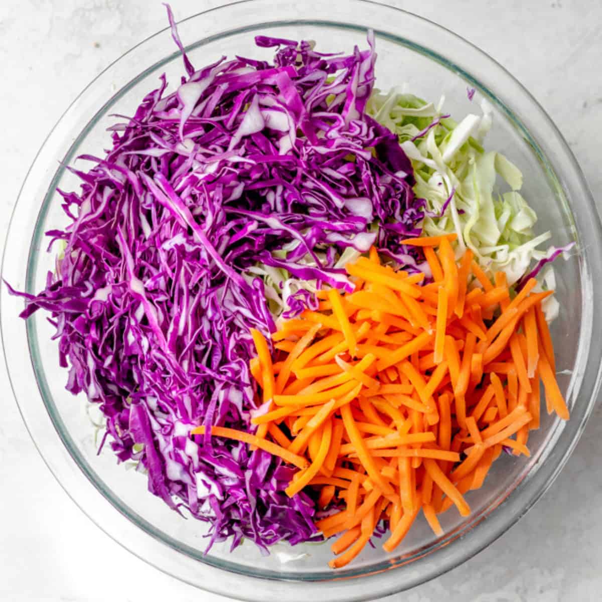 Shredded red and green cabbage and carrots in a bowl.