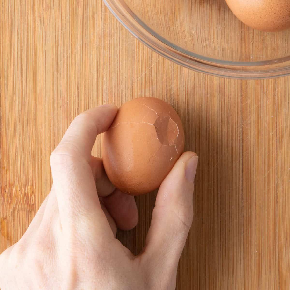 Tapping the egg on a hard surface with the shell cracked.
