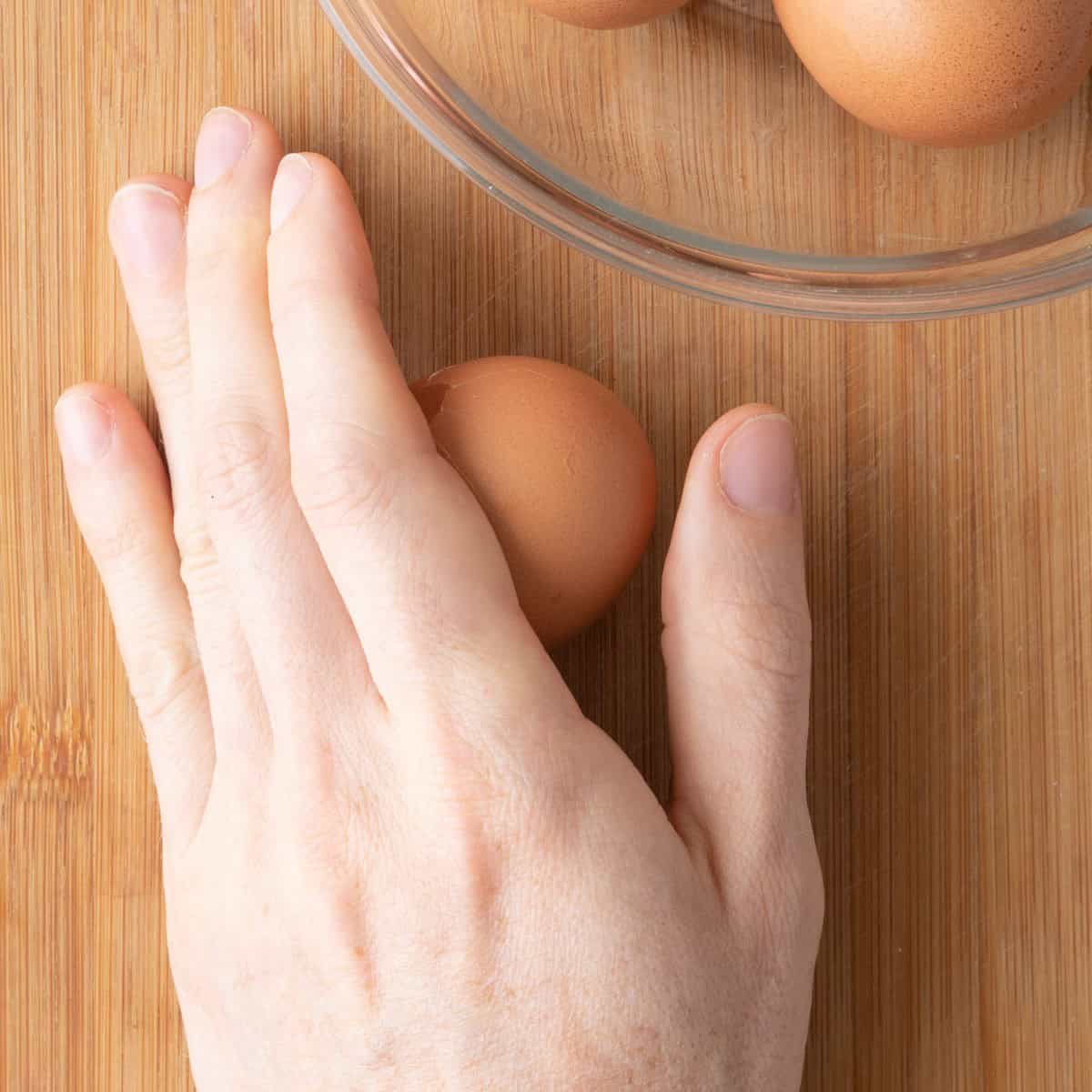 Gently rolling the egg between palm and countertop.