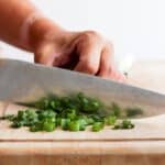Knife continuing to slice green onions.