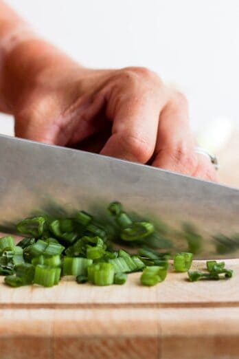 Knife continuing to slice green onions.
