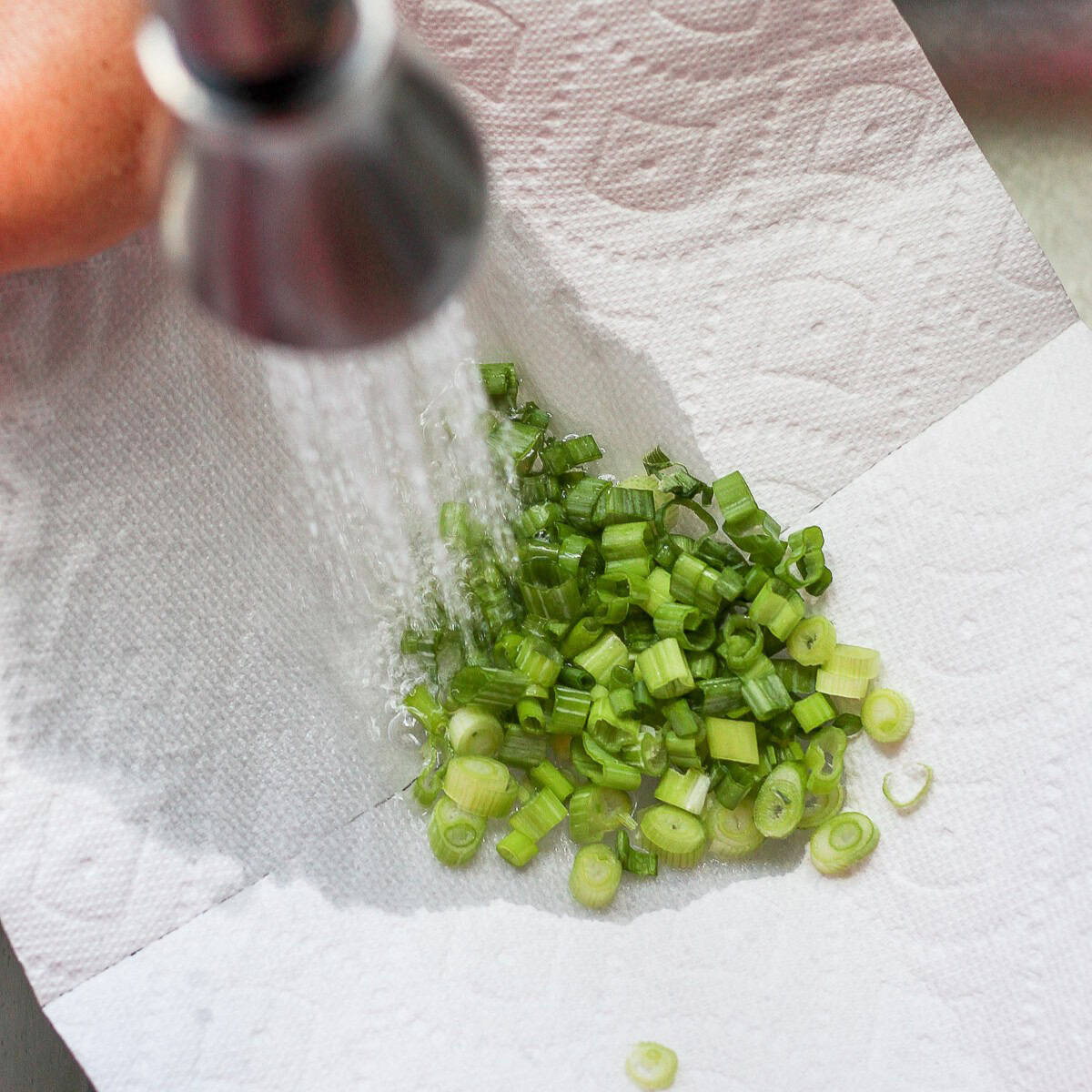 Rinsing chopped green onions under running water.