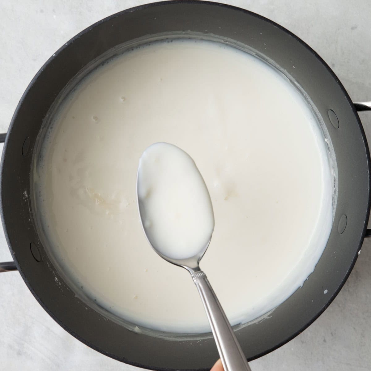 Cream after cooled to show thickened cream with spoon lifting some up.