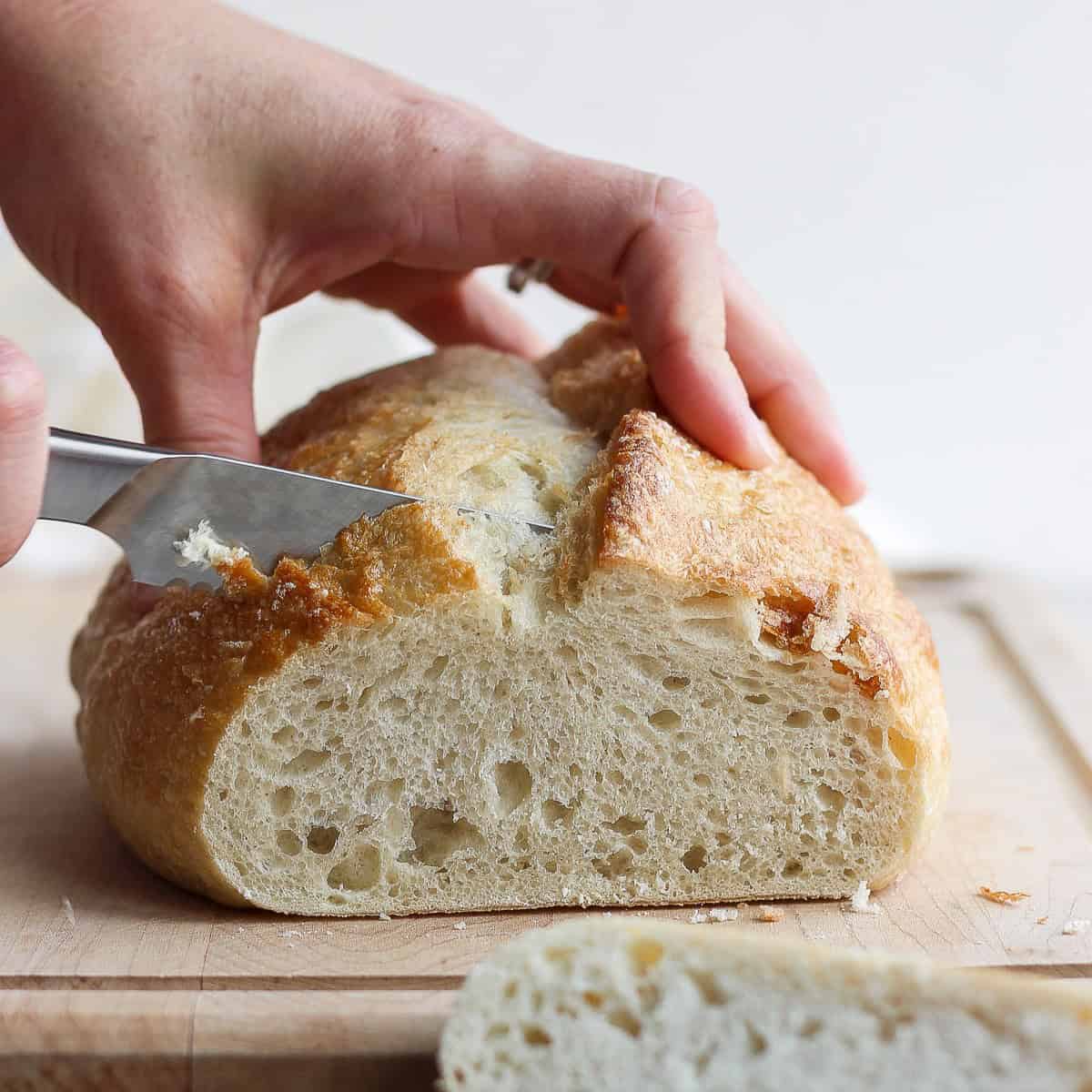 Knife cutting bread into thick slices.