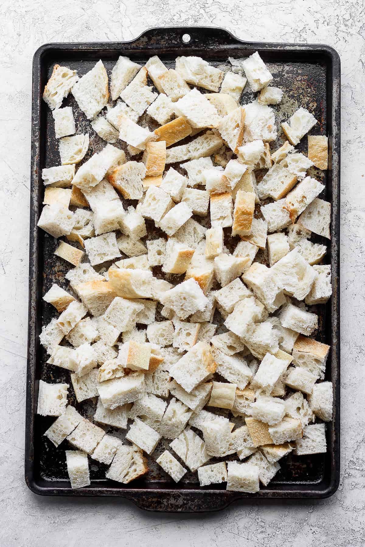 Cubed bread on baking sheet.