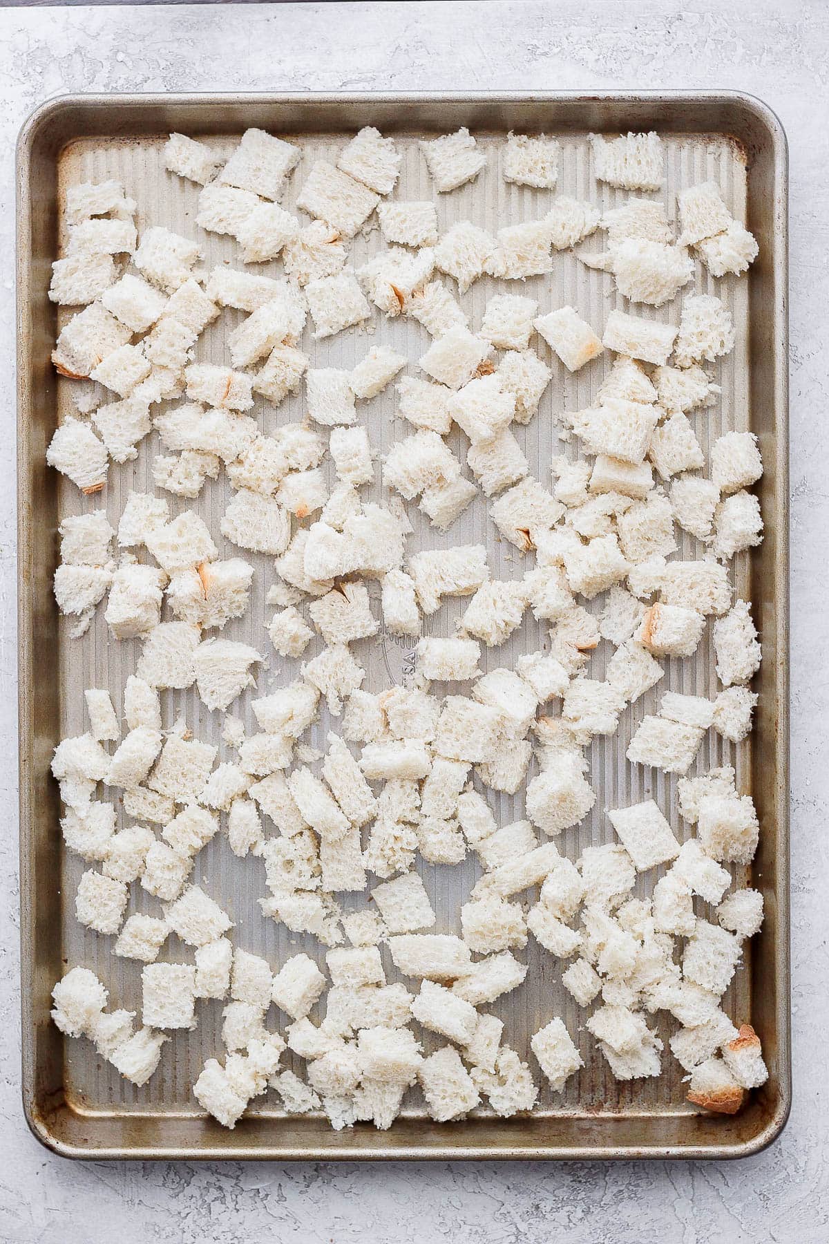 Cubed bread on a baking sheet.