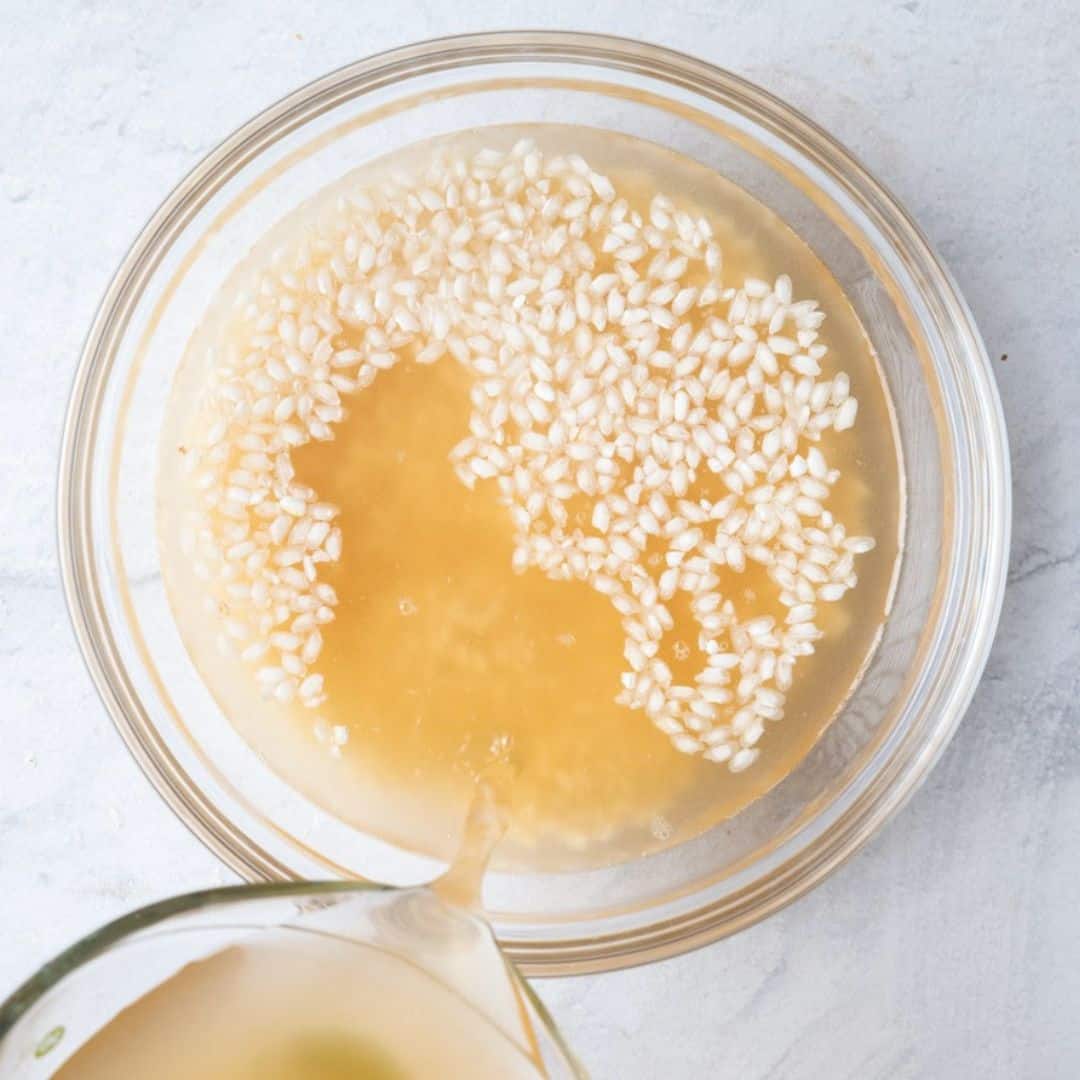 Pouring broth on top of rice in a bowl.