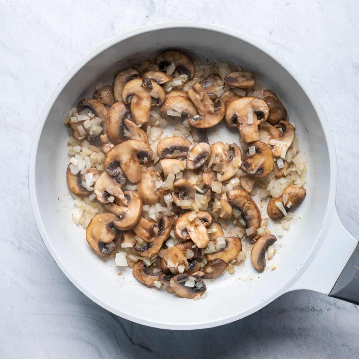 Cooked mushrooms with cooked onions and garlic.