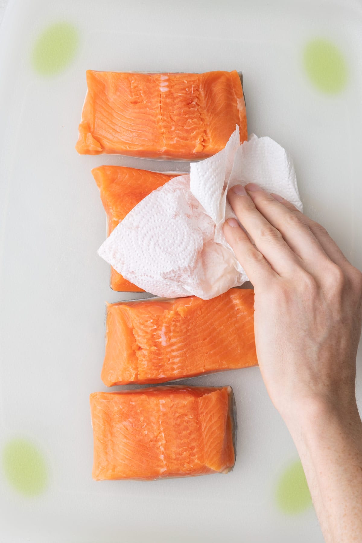 Patting salmon dry with paper towels.