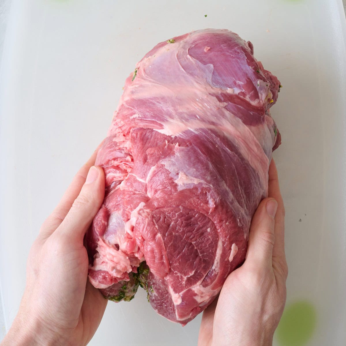 Hands rolling leg with herbs.