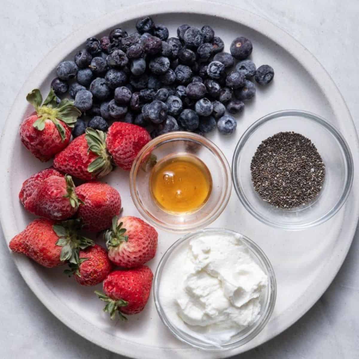 Ingredients for recipe: frozen blueberries, frozen strawberries, honey, chia seeds and yogurt.