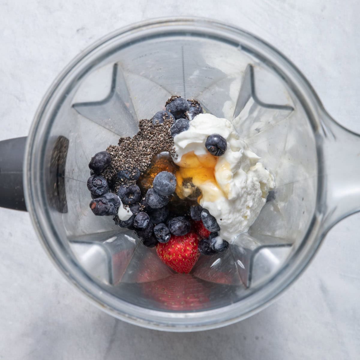 Strawberry blueberry smoothie ingredients in a blender.