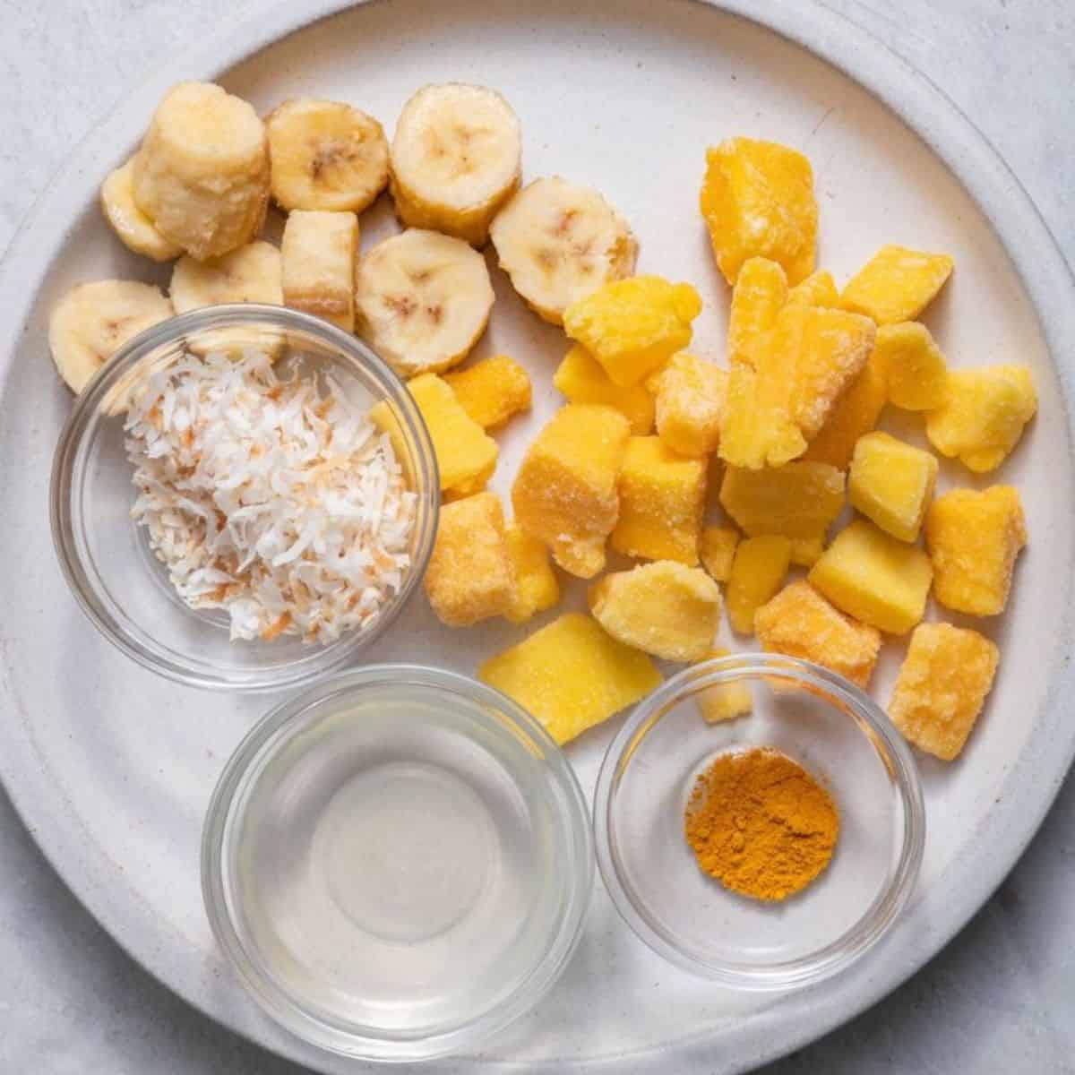 Ingredients for recipe: frozen banana slices, frozen mango, shredded coconut, coconut oil and turmeric.