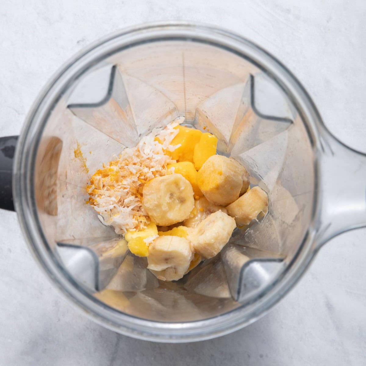 Mango banana smoothie ingredients in a blender.