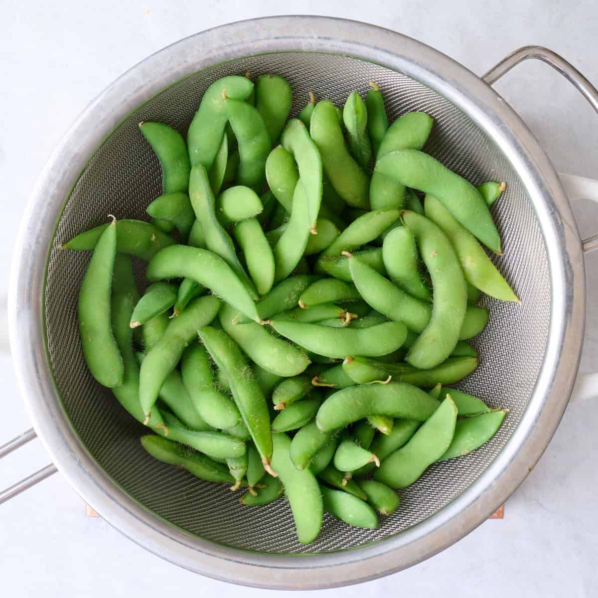 Cooked edamame in strainer of pot.