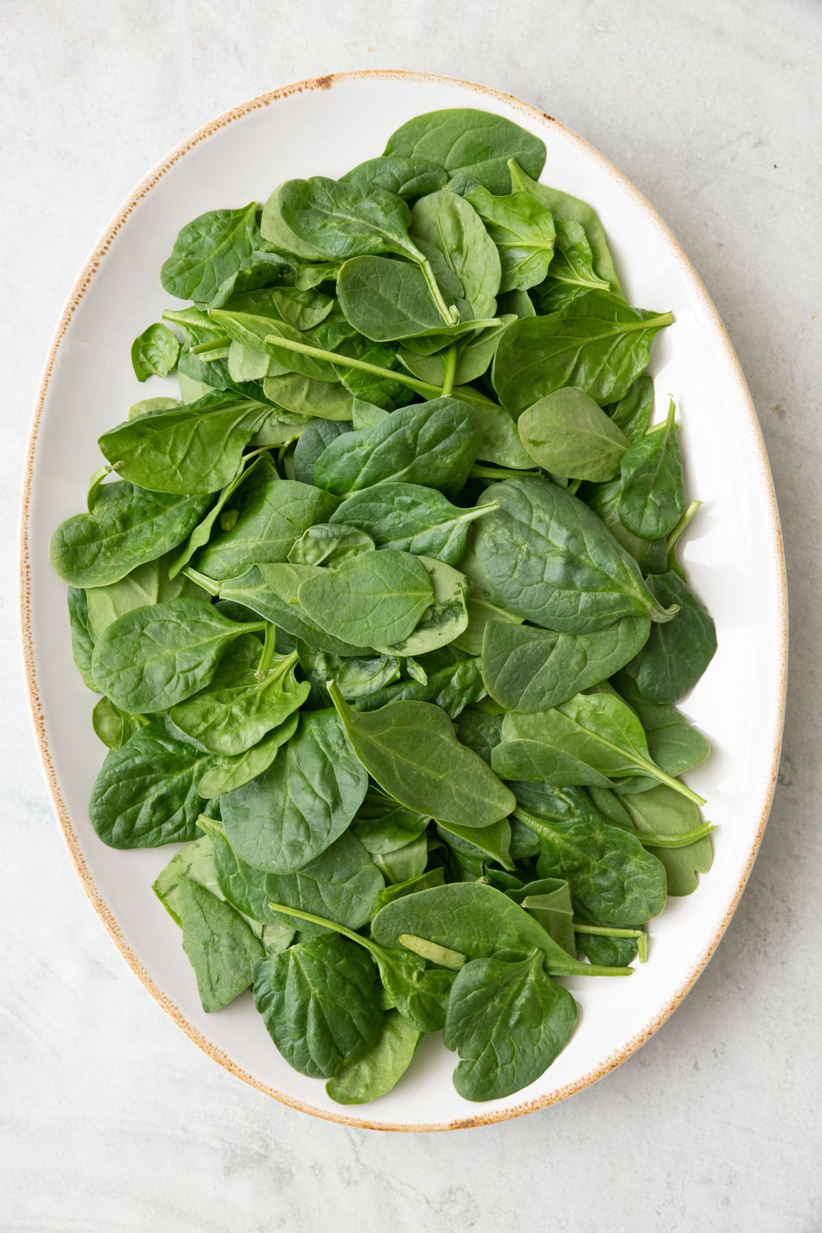 Fresh spinach leaves on a platter.