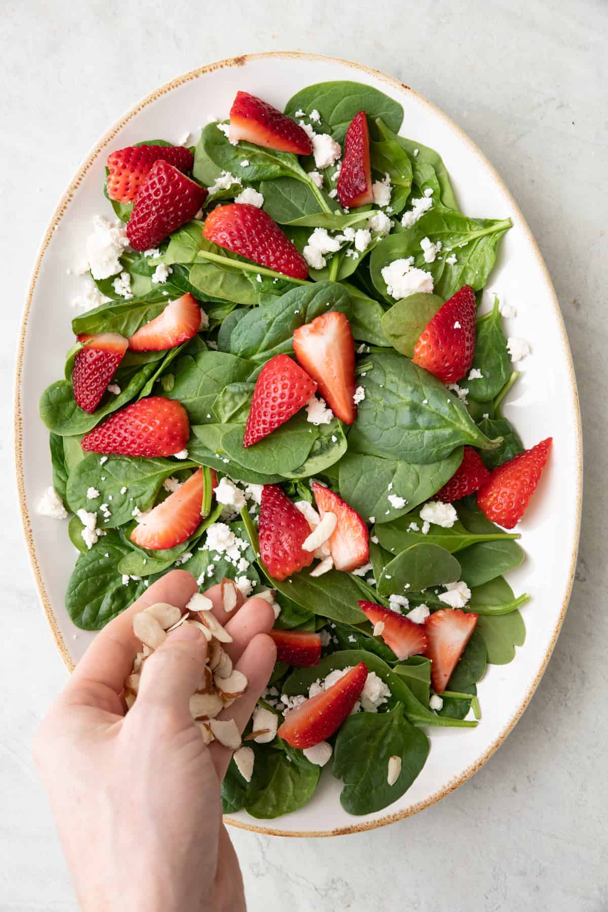 Fresh strawberries, crumbled feta cheese, and sliced almonds added on top of spinach.