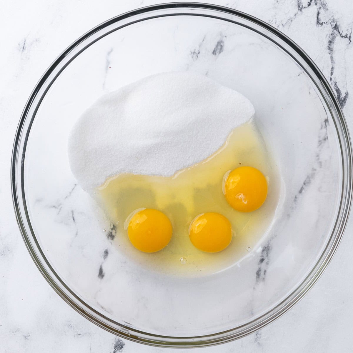 Eggs and sugar in a bowl before whisking.