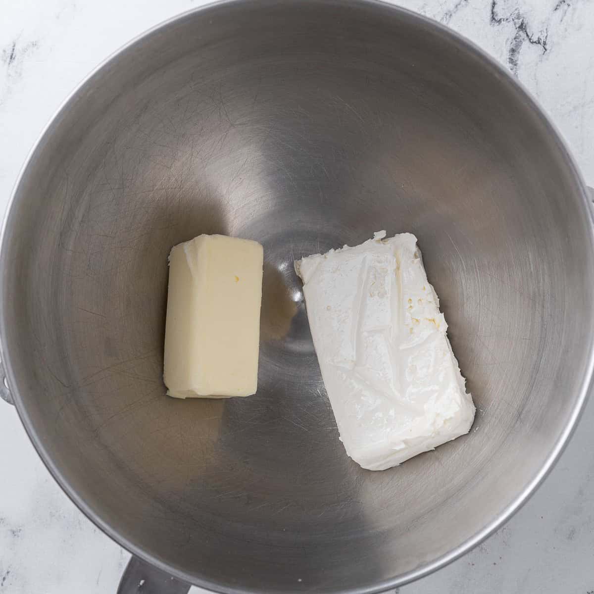 Cream cheese and butter in the bowl of a stand mixer.