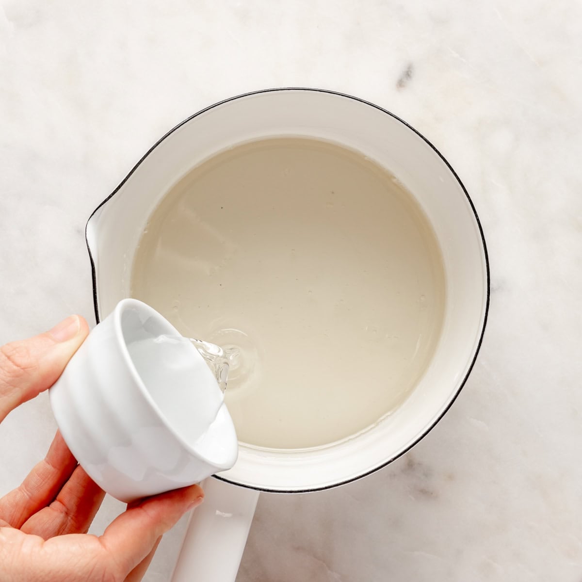 Pouring rose water into simple syrup pot.