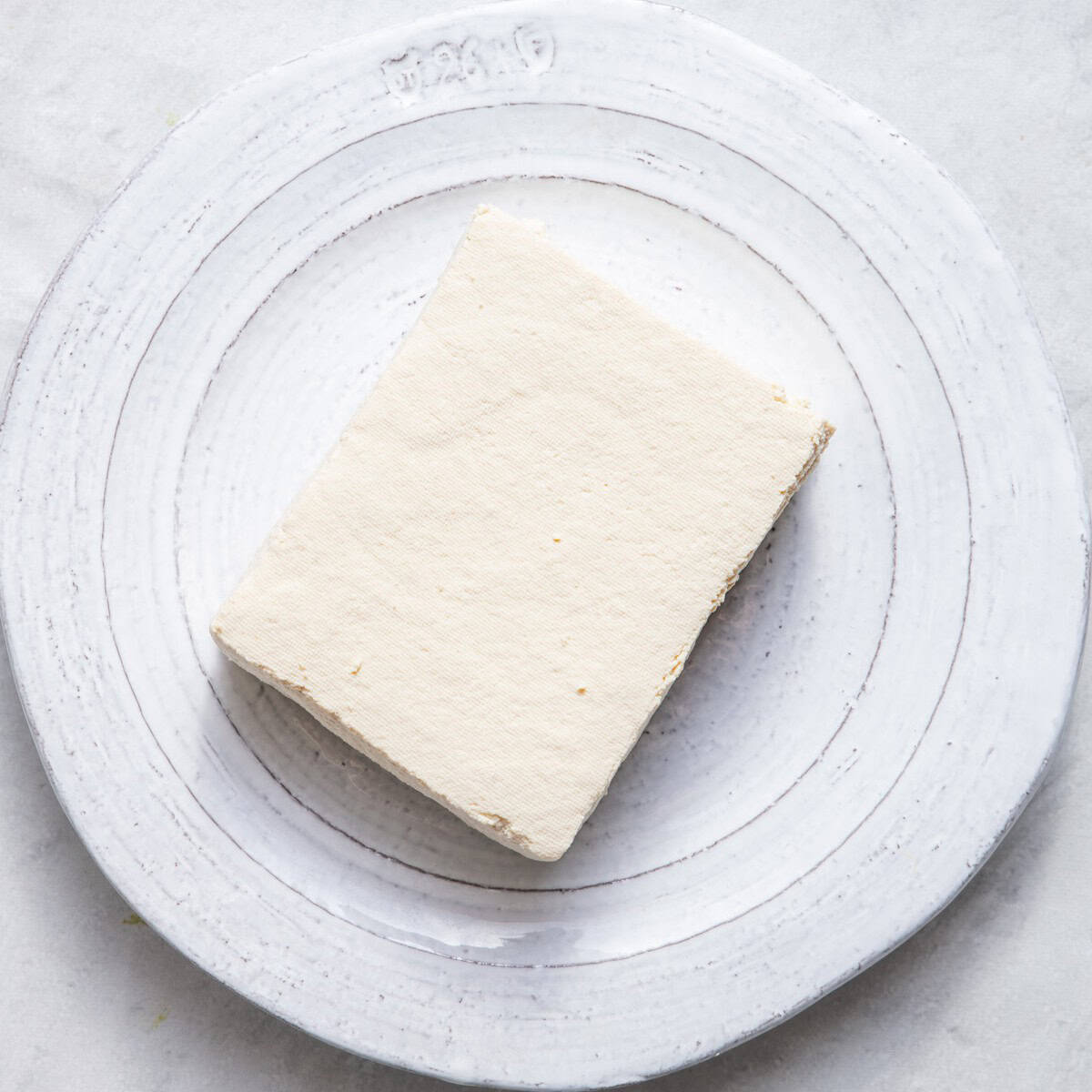 Tofu after pressed and dried on same plate.