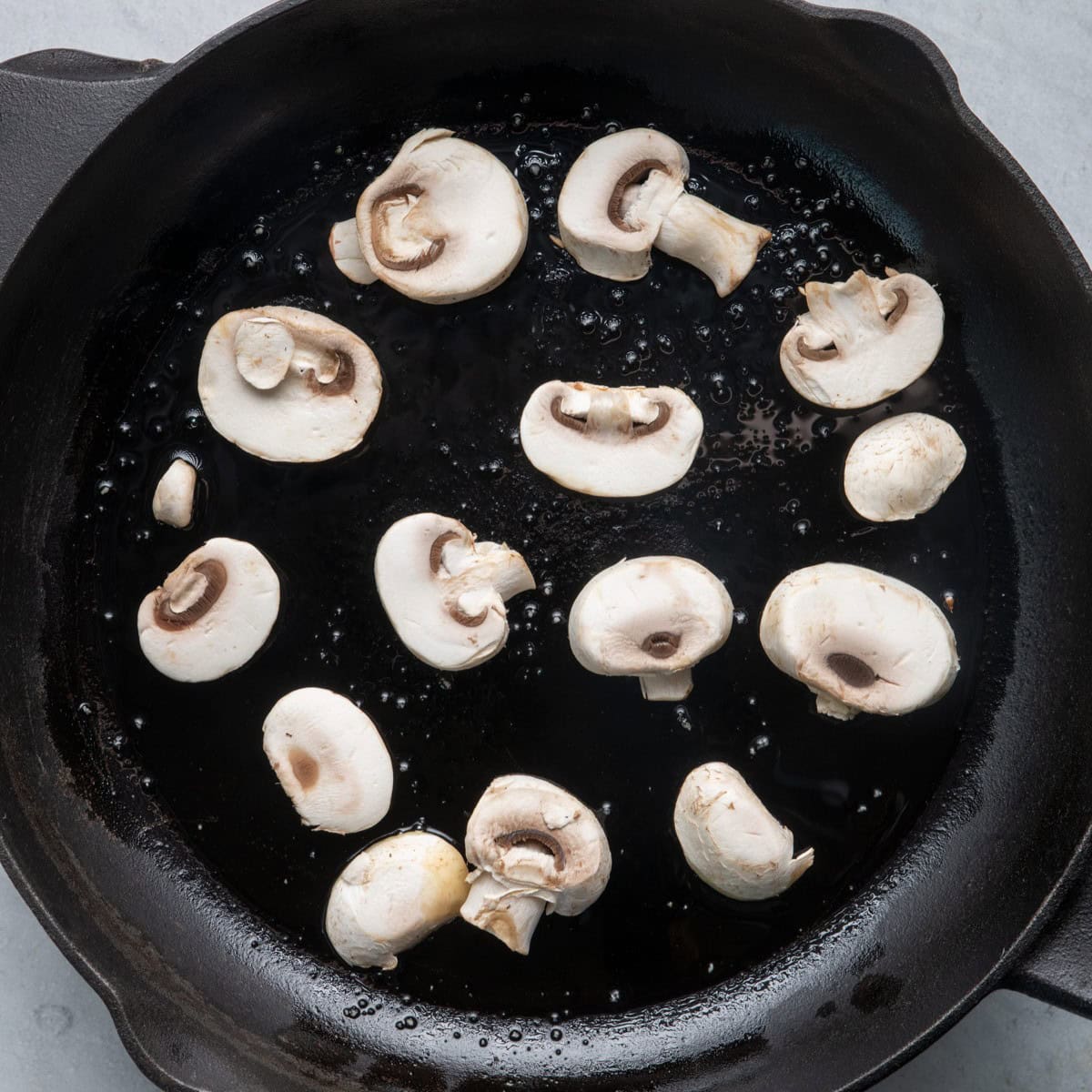 Olive oil and mushrooms in skillet.