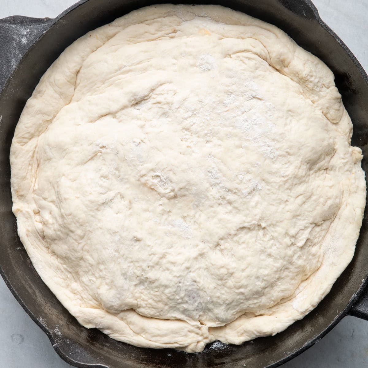 Pizza dough pressed on top of veggie, cheese and sauce mixture.