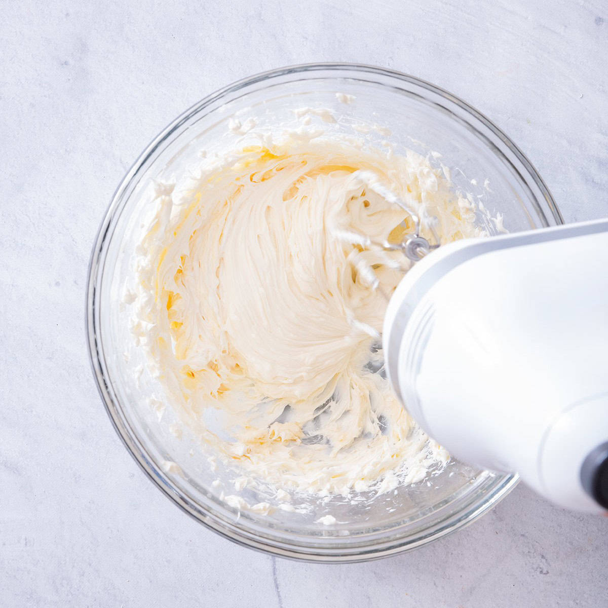 Mixing cream cheese with honey and vanilla in bowl.