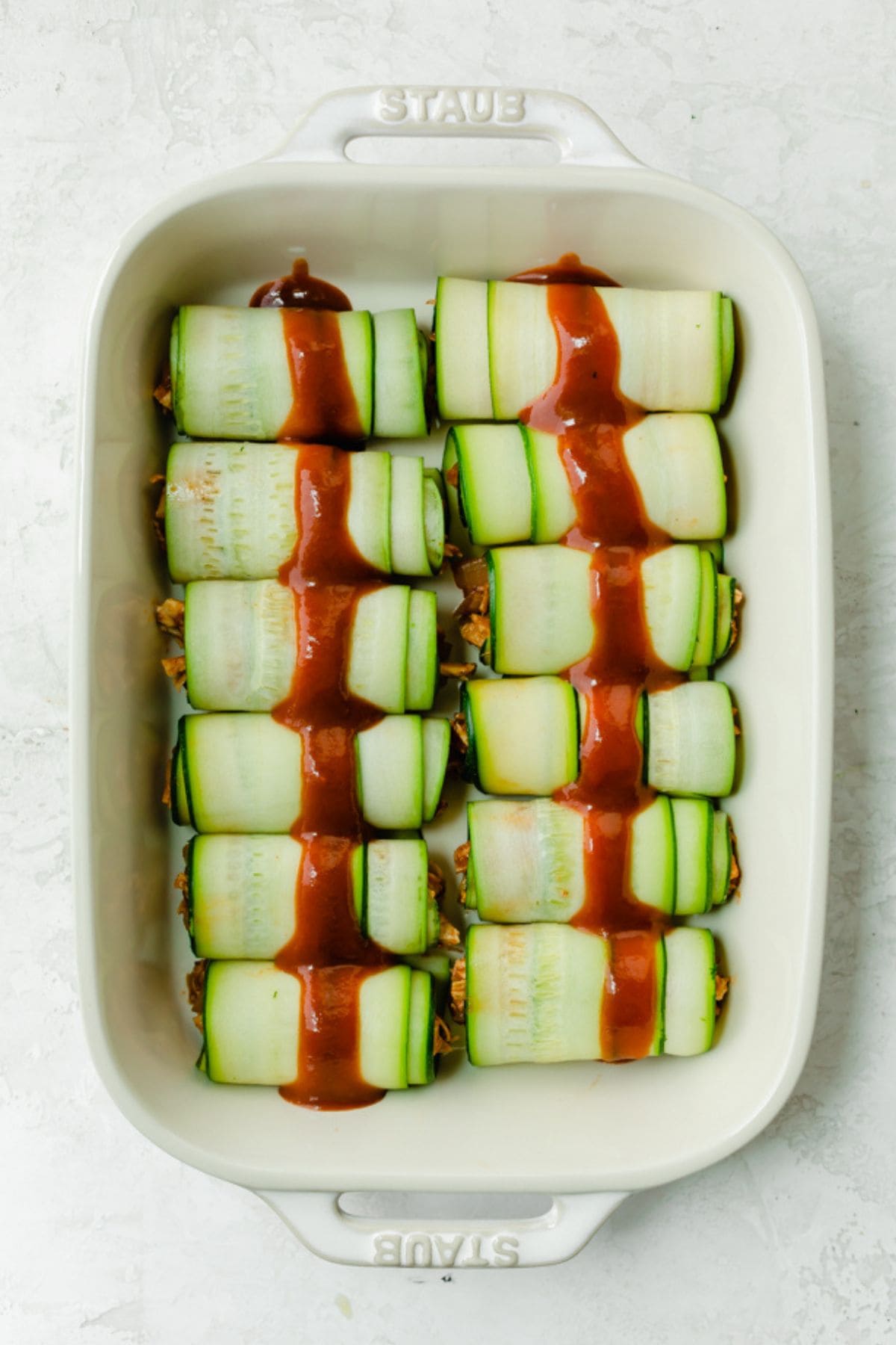 Recipe in baking dish with sauce on top.