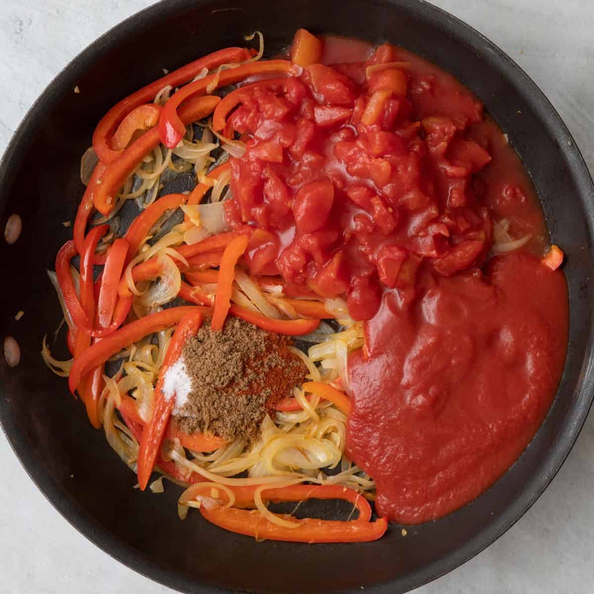 Tomatoes, tomato sauce, and seasonings added to pan before mixed.