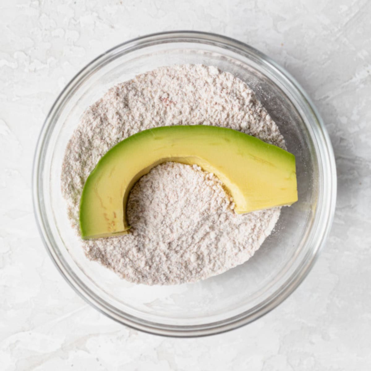 A sliced avocado on top of flour.