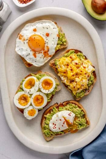 Avocado toast with 4 different styled eggs: sunny side up, scrambled, sliced boiled eggs, and poached.