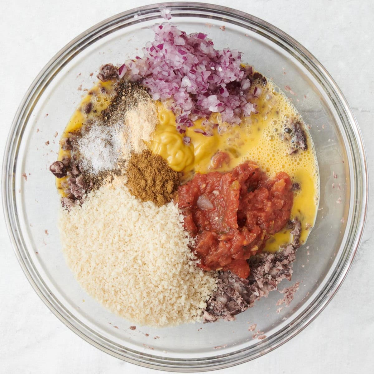 Beans in a bowl after mashing with remaining ingredients added before mixing.
