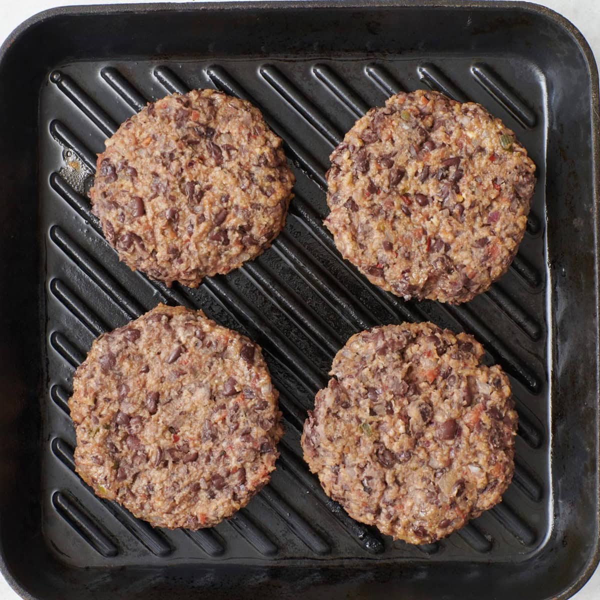 Vegetarian burger patties on a grill pan before cooking.