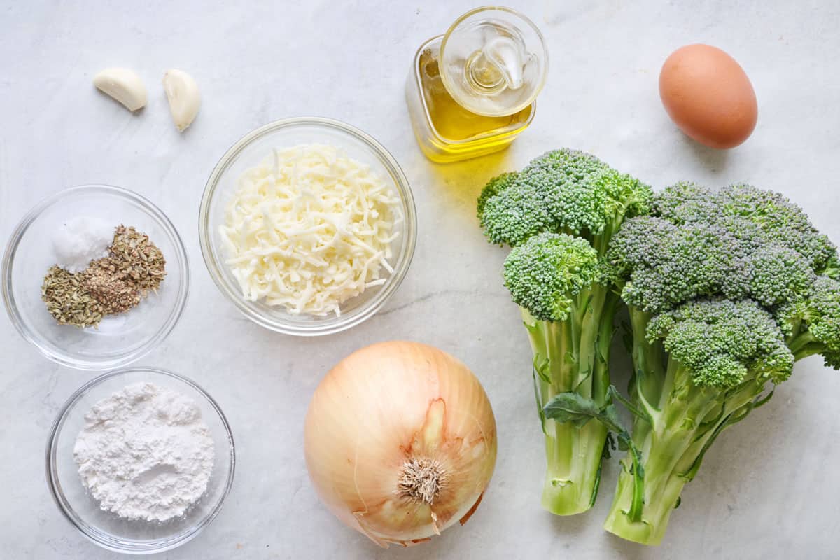 Ingredients for recipe: garlic, seasonings, shredded cheese, flour, onion, oil, egg, and broccoli.