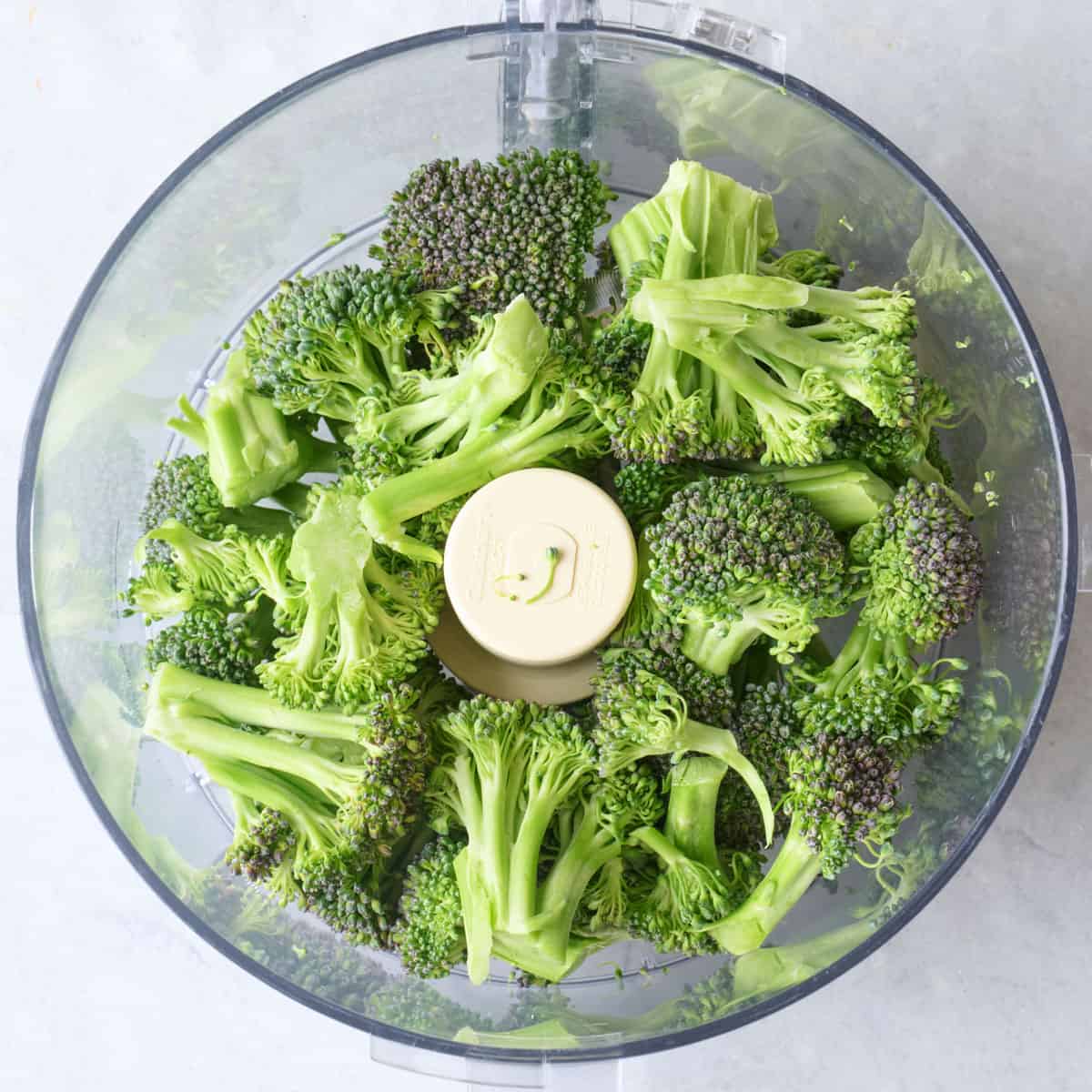 Broccoli florets in the bowl of a food processor.