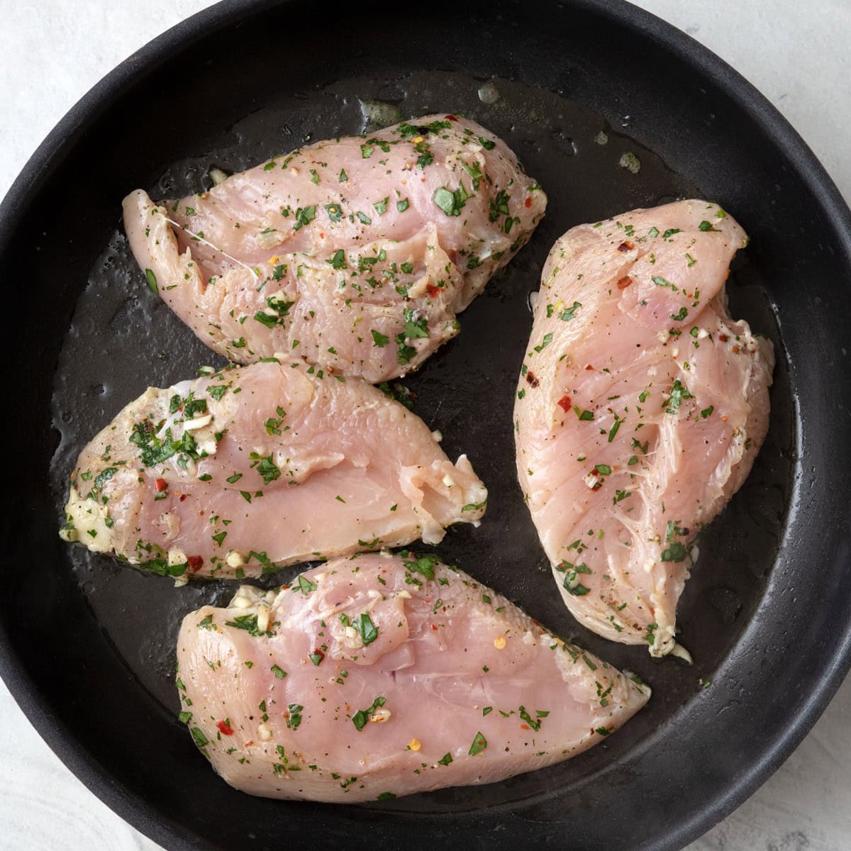 Seasoned chicken breast in a skillet.