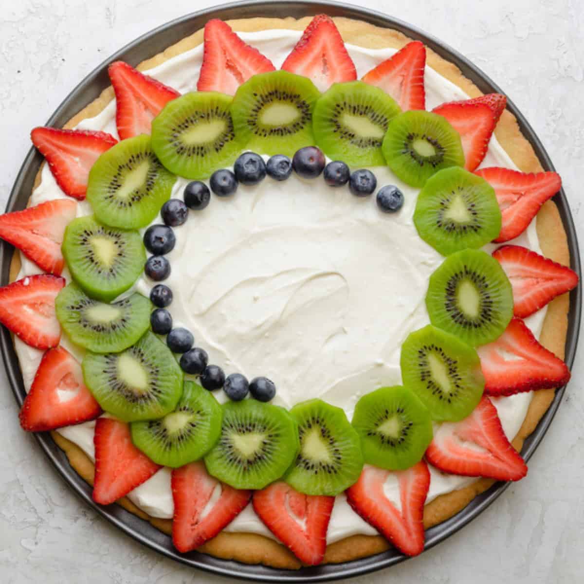 Layering fresh fruit on top of cookie with cream.