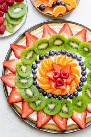 Fruit pizza decorated with strawberries, kiwi, blueberries, clementines and raspberries.