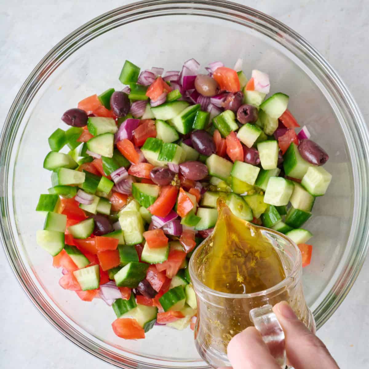 Pouring dressing over tossed veggies.