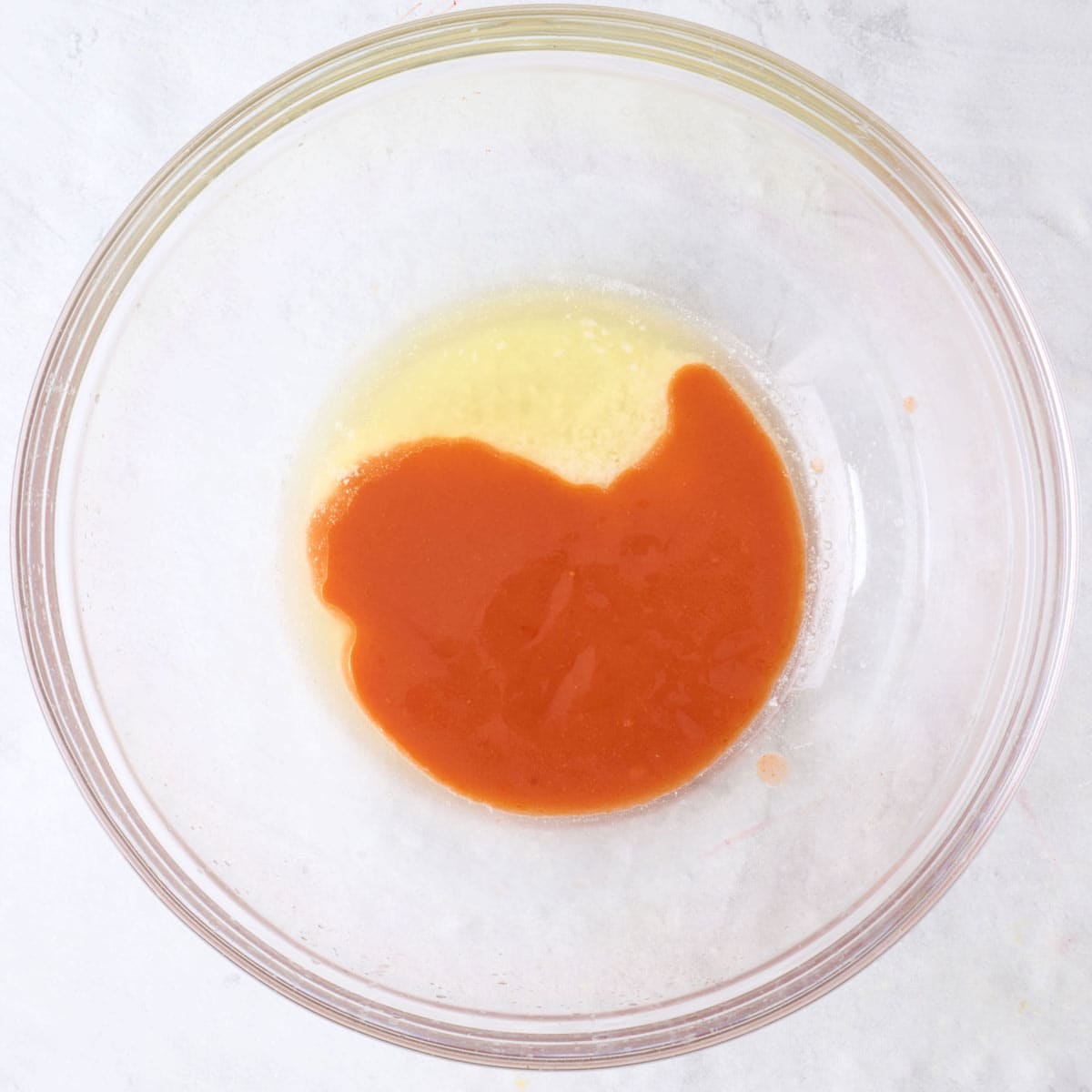 Hot sauce and melted butter in a bowl.