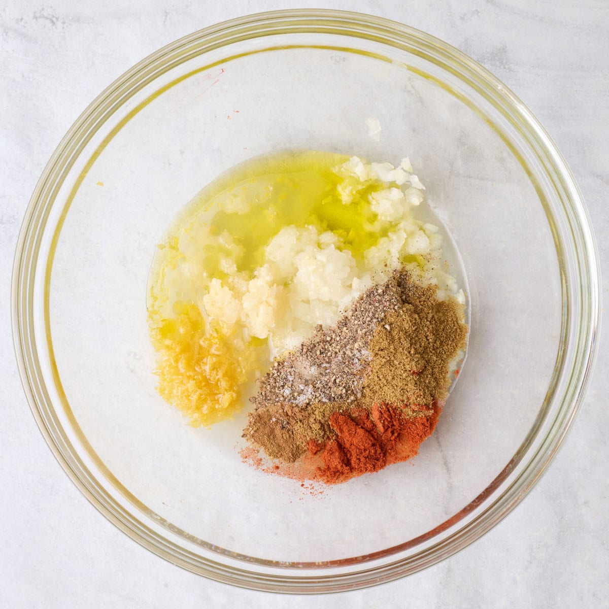 Grated onion, garlic, oil, lemon zest and juice, and seasonings in a large bowl.